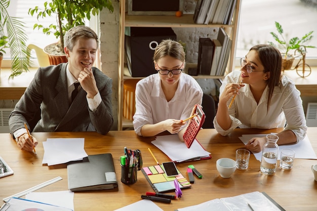 Creative process. Group of young business professionals having a meeting. Diverse group of coworkers discuss new decisions, plans, results, strategy. Creativity, workplace, business, finance, teamwork