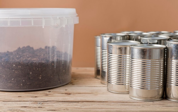 Creative recycling at home aluminum cans and recycled plastic container with soil on garden wooden