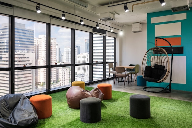 Creative room coworking space with cushions and chairs on artificial grass in modern office