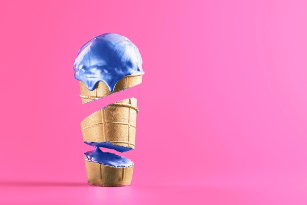 창의적인 판매 개념 복사 공간이 있는 밝은 분홍색 배경에 파란색 녹는 아이스크림으로 와플 컵을 잘라냅니다.