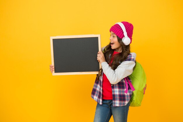 Creative school. Happy child hold school blackboard. Little girl back to school. Primary schoolchild yellow background. Music lesson. School and education. Never stop learning, copy space.