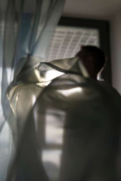 Foto siluetta creativa dell'uomo attraverso le tende e le ombre delle finestre