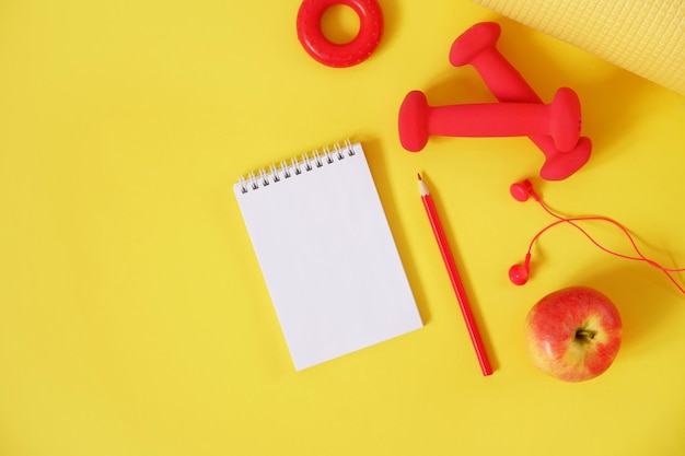 Creativo sport fitness concept manubri cuffie mano expander apple notebook matita su un giallo