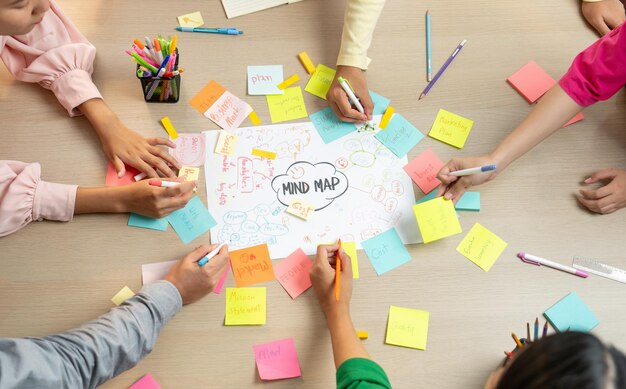 Foto gruppo creativo di startup brainstorming idea d'affari giovani e bellissimi imprenditori che lavorano insieme e condividono l'idea scrivendo in note adesive colorate concentrarsi sulla mano top view variegato