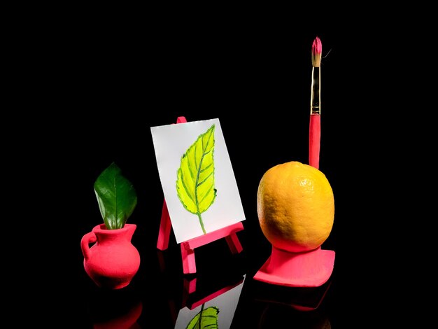 Creative still life with lemon at the easel on a black background