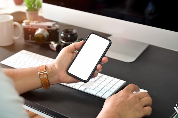 空白の画面の携帯電話を持っている創造的なスタイリッシュな手