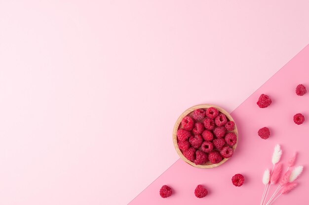 Foto sfondio estivo creativo fatto di bacche fresche e fiori su rosa spazio di copia piatto