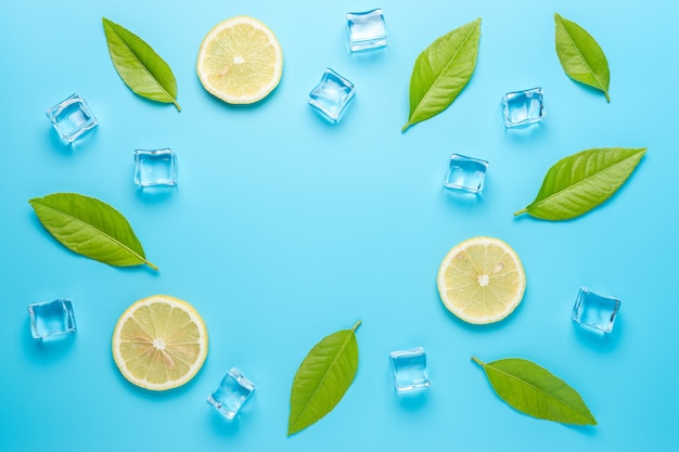 Creative summer composition with sliced lemon and ice cubes on blue surface.