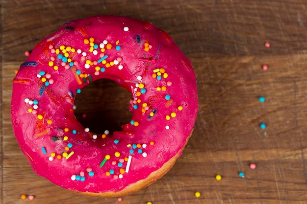 Creative sweet food Glazed colorful donut on a wooden background