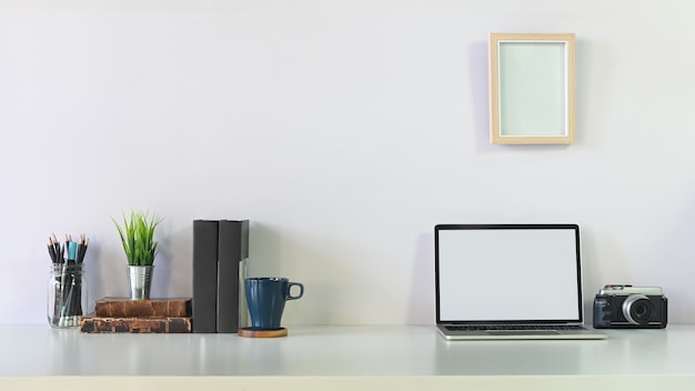 Creative table laptop, camera, coffee, notebook, pencil and photo frame on workspace table.