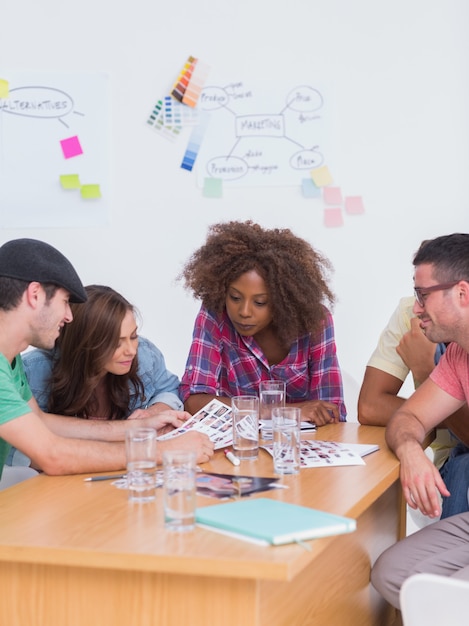 Creative team talking over contact sheets in meeting