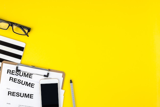 Creative top view flat lay of desk with resume documents copy space on bold yellow background in minimal style.