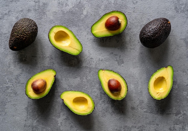 Creative top view of sliced and whole avocados on a grey surface