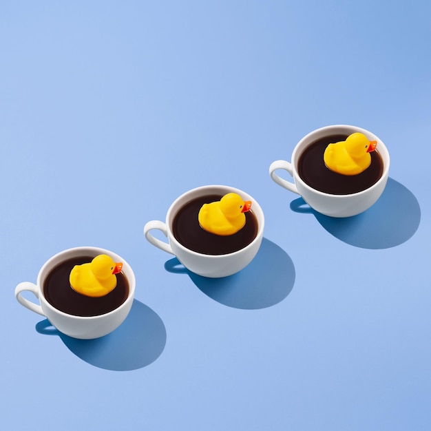 Photo creative trendy pattern made of coffee cup with a yellow rubber duck on a blue background