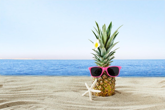 모래 해변에서 선글라스를 쓴 창의적인 열대 파인애플