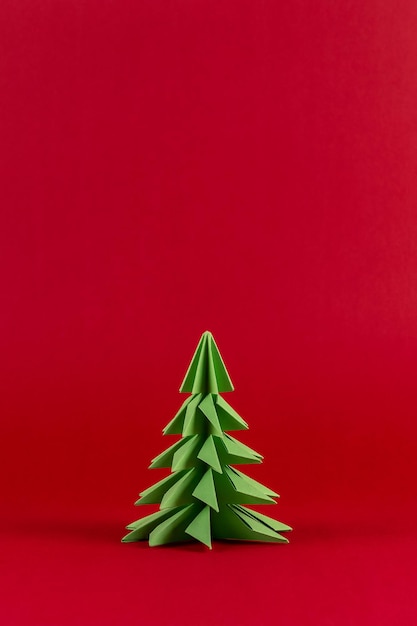 Creative winter background with paper Christmas tree on red backdrop