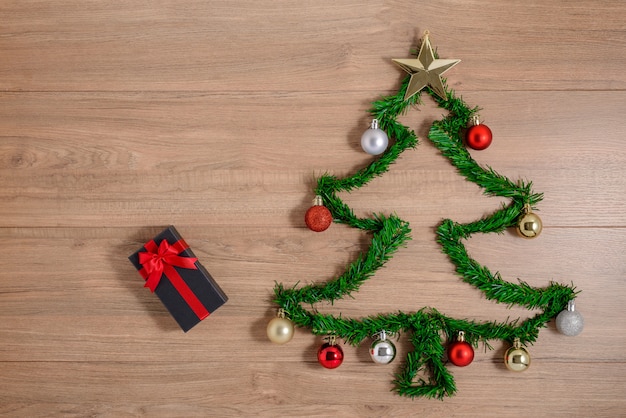 Creative winter layout made with evergreen tree branches and ornament, gift boxes on wooden board