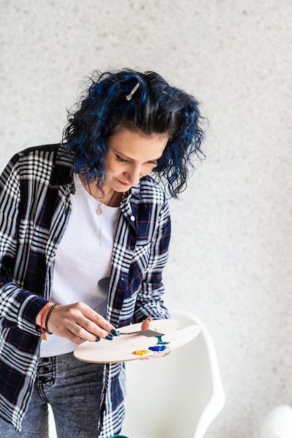 Creative woman artist putting oil paints on palette working in her studio