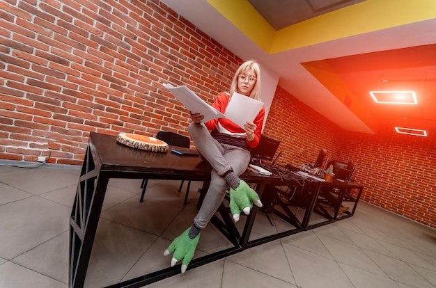 Creative woman sitting at the desk in her modern office\
interior while looking at the documents and working program\
development concept