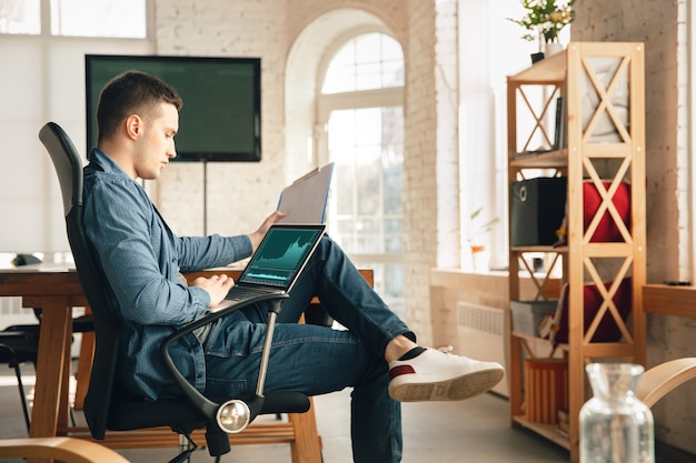 Creative workplace - organized work space as you like for inspiration. Man working in office in comfortable attire, relaxed position and messy table. Choose atmosphere you want - ideal clear or chaos.