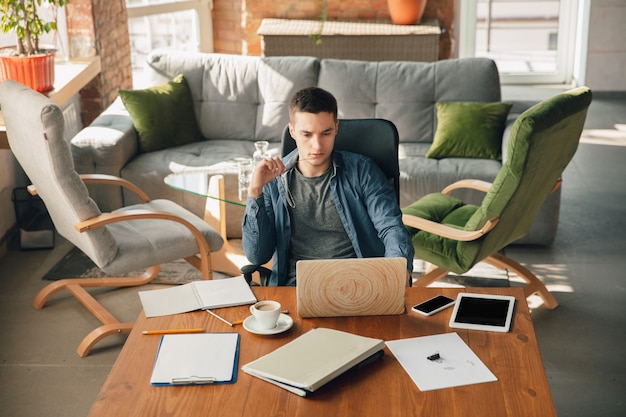 Creative workplace - organized work space as you like for inspiration. Man working in office in comfortable attire, relaxed position and messy table. Choose atmosphere you want - ideal clear or chaos.