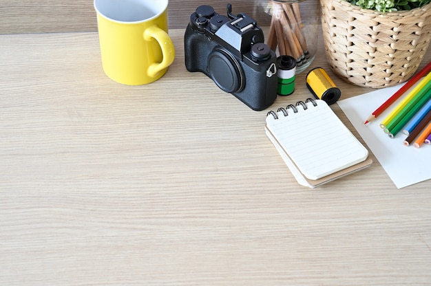 Creative workspace camera and office supplies on wood desk.