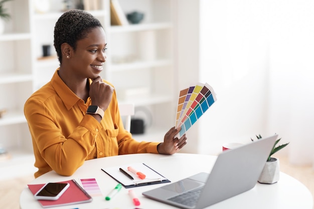 Creative young black woman designer working on laptop