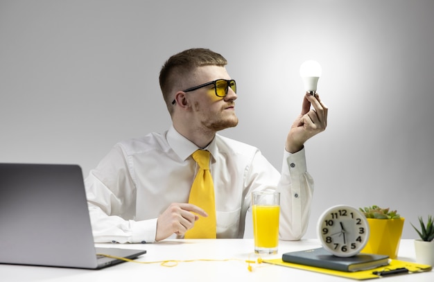 Creative young man looking at burning light bulb in hand. Startup business idea