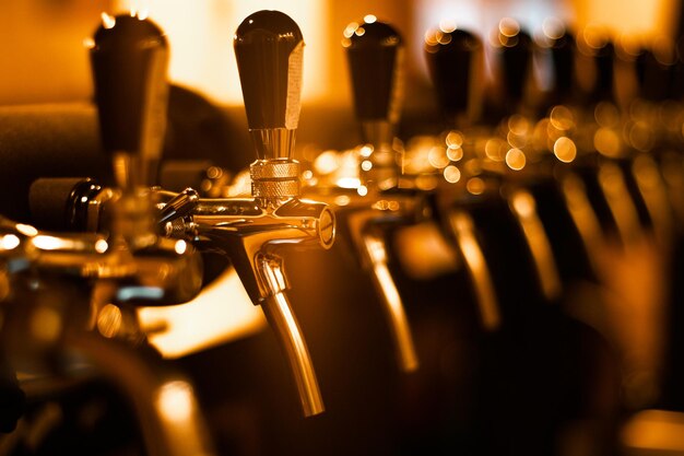 Creatively blurred faucets in beer pub with defocused bokeh and artistic digital noise Golden row of taps in taproom