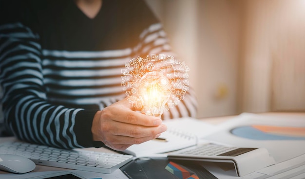 Creativiteit en innovatie zijn sleutelsuccesconcept, zakenmanhand die gloeilamp vasthoudt met rekenmachine om te berekenen en geldstapel. idee energie besparen en boekhoudkundige financiën in kantoorconcept