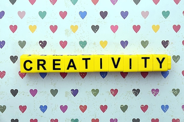 Creativity motto by alphabet letters on surface with hearts on background