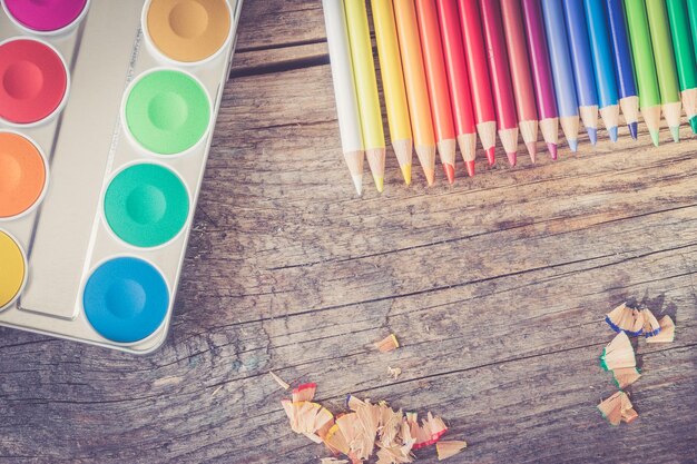 Creativity Multicolored pencils water colors and brushes on rusty wooden table