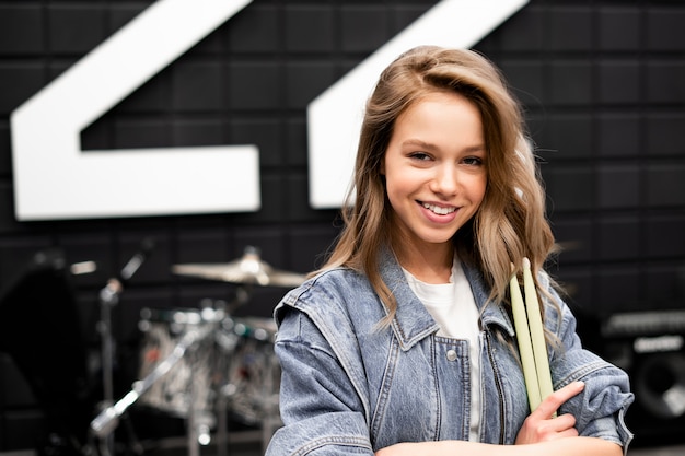 Creativity and music. Young beautiful girl plays the drums. Face close up. Drumsticks. Recording Studio. Musical equipment.