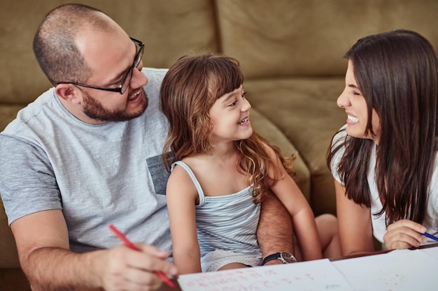 Photo creativity runs in this family shot of a mother and father drawing together with their young daughter at home