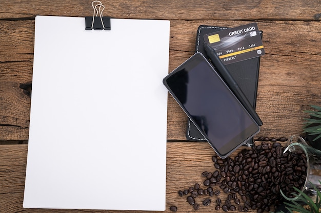 Credit card document smartphone coffee beans placed on a wooden table top view