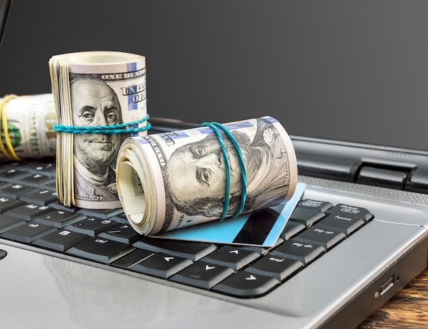 Credit card and dollar bills on the laptop keyboard Internet business and online making money concept