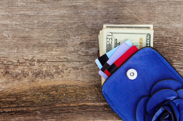 Credit card and dollars in wallet on wooden