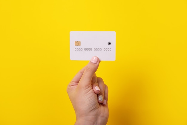 Credit card in hand, card with electronic chip over yellow background