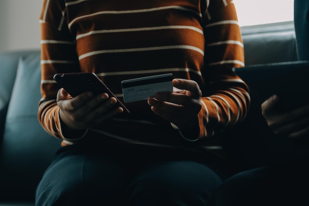 Photo a credit card in the hands of a young businesswoman pays for a business on a mobile phone and on a desk with a laptop