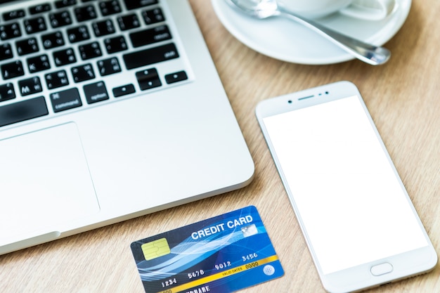 Credit card of laptop computer,smartphone and coffee cup on wood