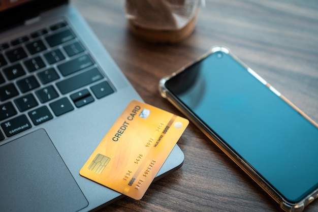 Credit card of laptop computer,smartphone and coffee cup on wooden background,Online banking Concept