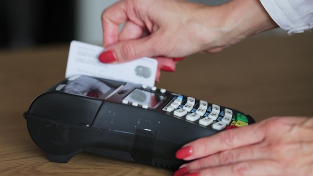 お金の取引のためのクレジット カード マシン クレジット カードを持つ女性手 pos 端末をスワイプし、ピン コードを入力します 電子マネーの銀行サービス 経済的な成功と安全