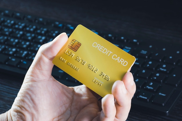 Credit card mockup in the hand with computer keyboard background