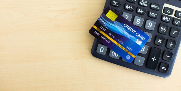 Credit card for pay with black calculator on wood table.