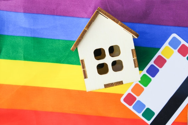 クレジットカードと虹色の旗の上の小さな木造住宅