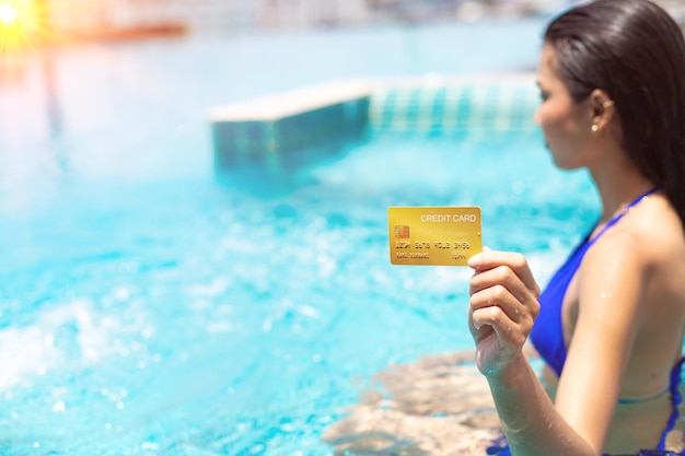인식할 수 없는 여자 손에 신용 카드 강한 태양 아래 수영장에서 아름 다운 소녀