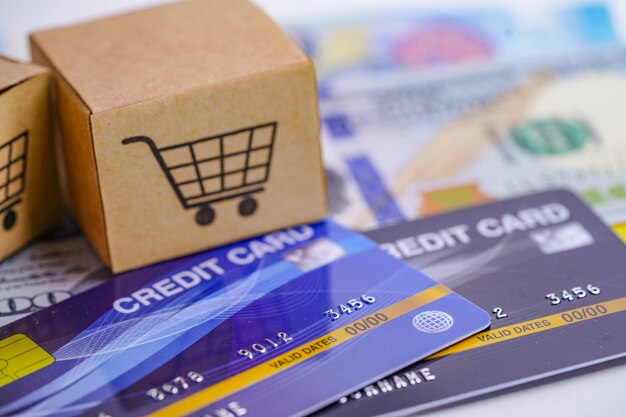 Credit card and US dollar banknotes with shopping cart box.