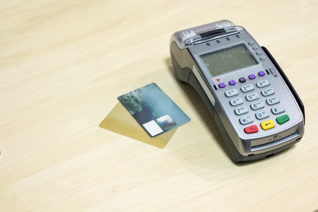Credit card with payment terminal on wood desk