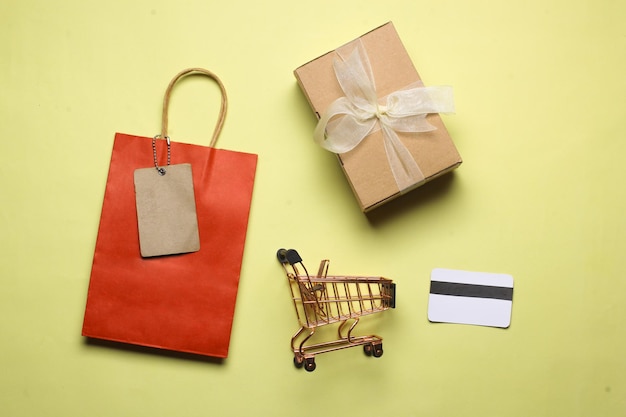 Credit cards, shopping bag, boxes, and miniature trolley are isolated on yellow background.