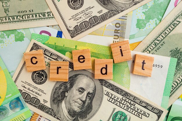 CREDIT inscription on wooden cubes on the texture of us dollars and euro banknotes
